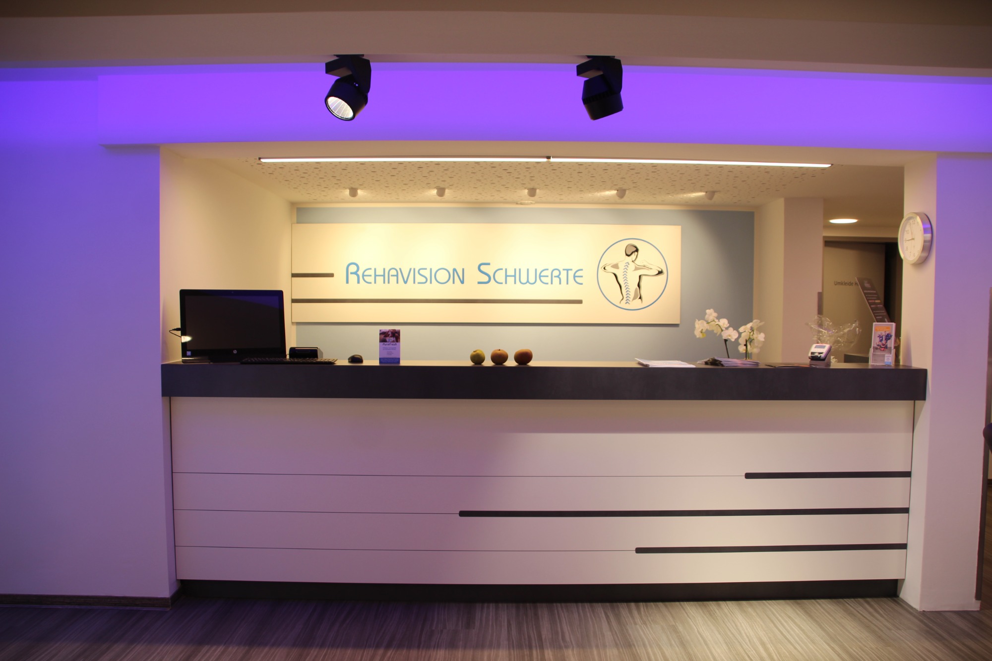 Moderne Empfangstheke mit informativer Beschilderung in einem hellen, einladenden Raum.