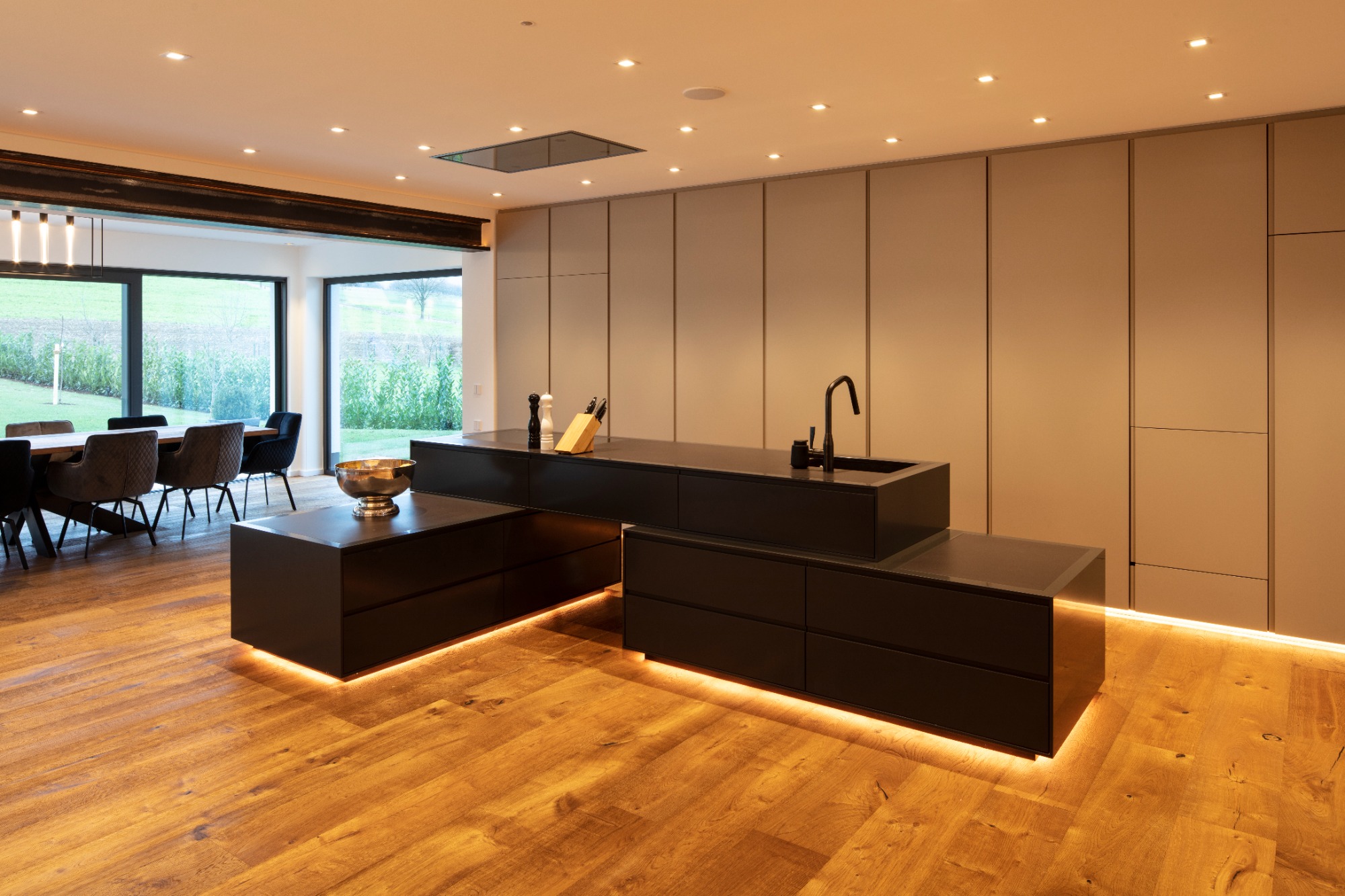 Moderne Küchenzeile aus Schwarz, mit Holzfußboden und eleganter Beleuchtung.