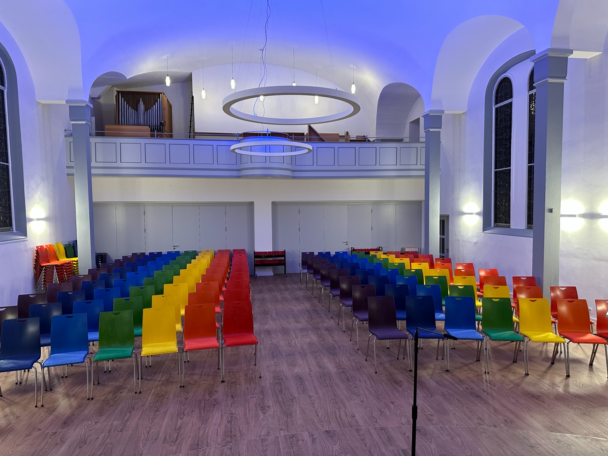 Bunte Stühle in einer modernen Veranstaltungsstätte, angeordnet in Reihen.