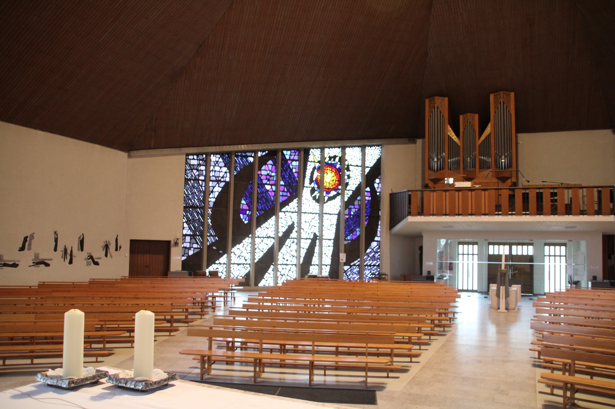 Katholische Kirche Höchsten Lichplannung Moderne Kirche mit Holzbänken, buntem Glasfenster und Orgel im Hintergrund.