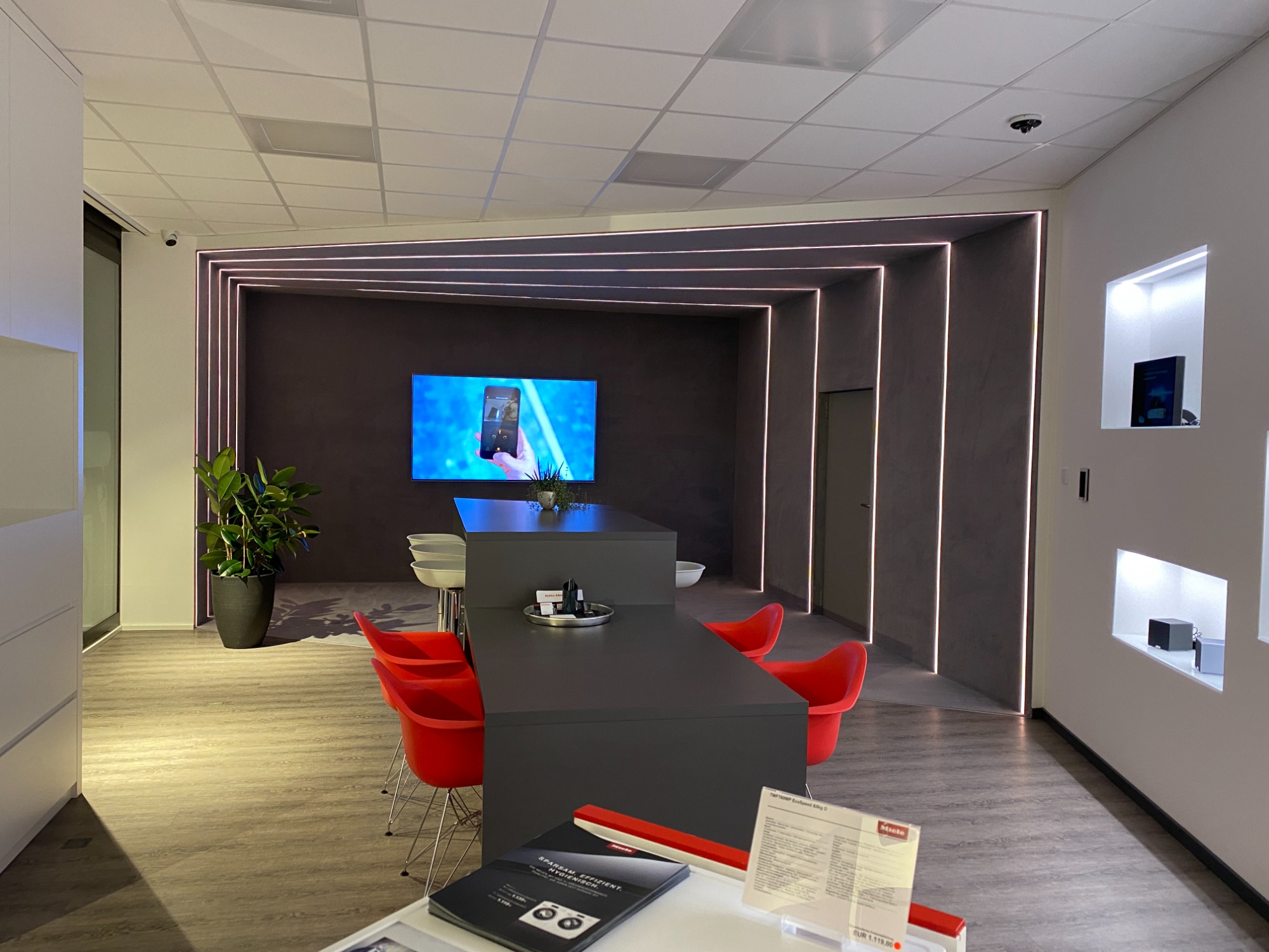 Moderne Büroumgebung mit rotem Stuhlkreis und großem Bildschirm an der Wand.